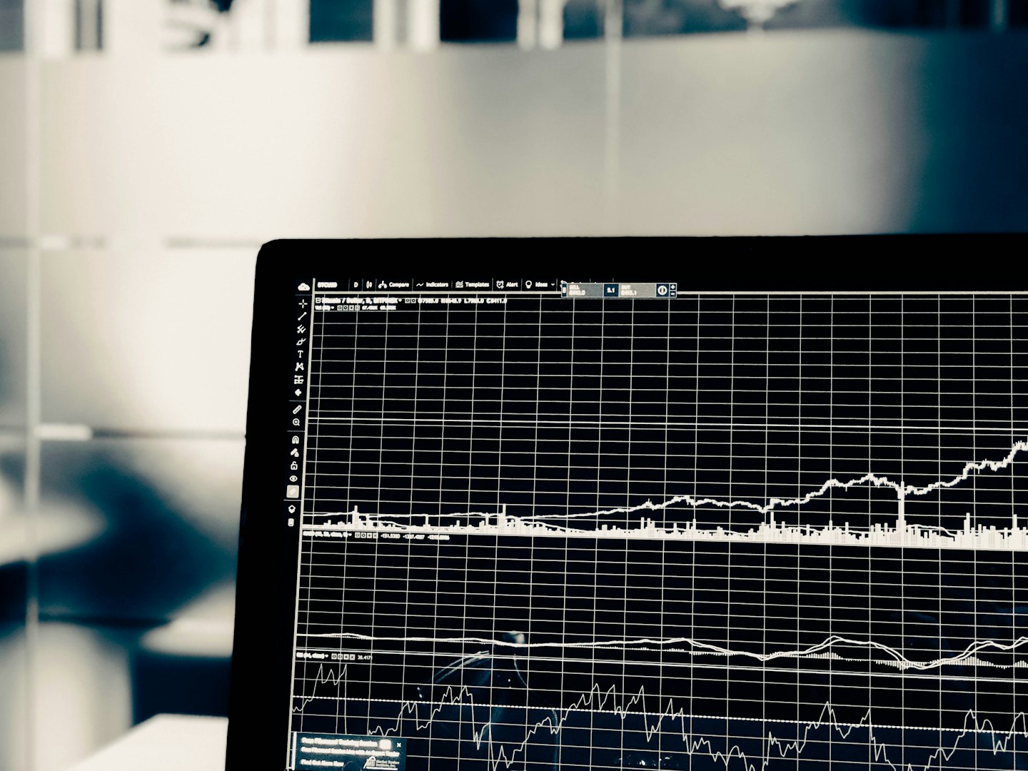 Laptop screen displays financial charts and graphs on a black background.